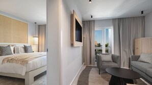 A modern hotel room with a bed, a sofa, a TV, and a balcony view. - Beach Bay Hvar Hotel (Hvar)