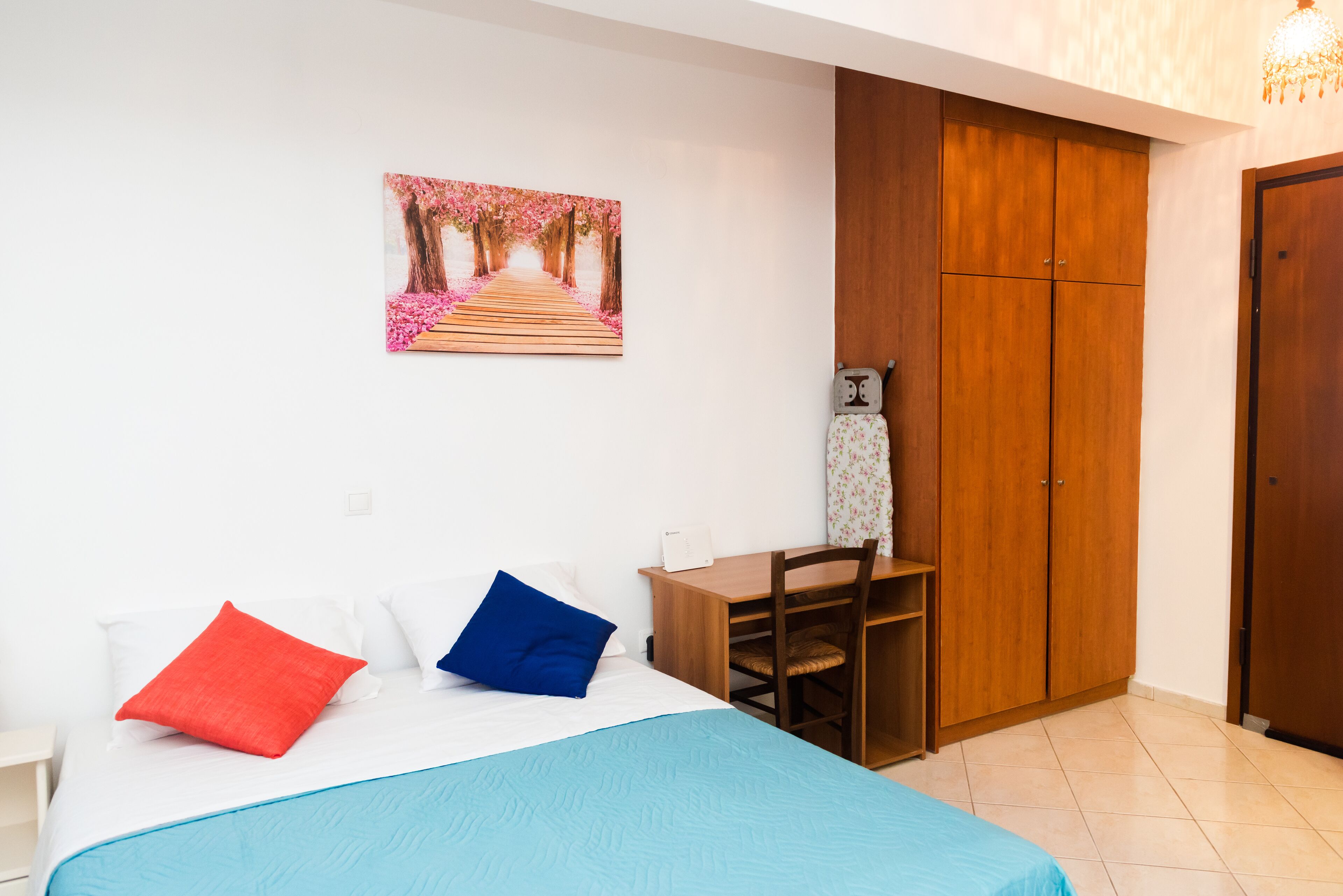 A bedroom with a bed, a desk, and a wardrobe.