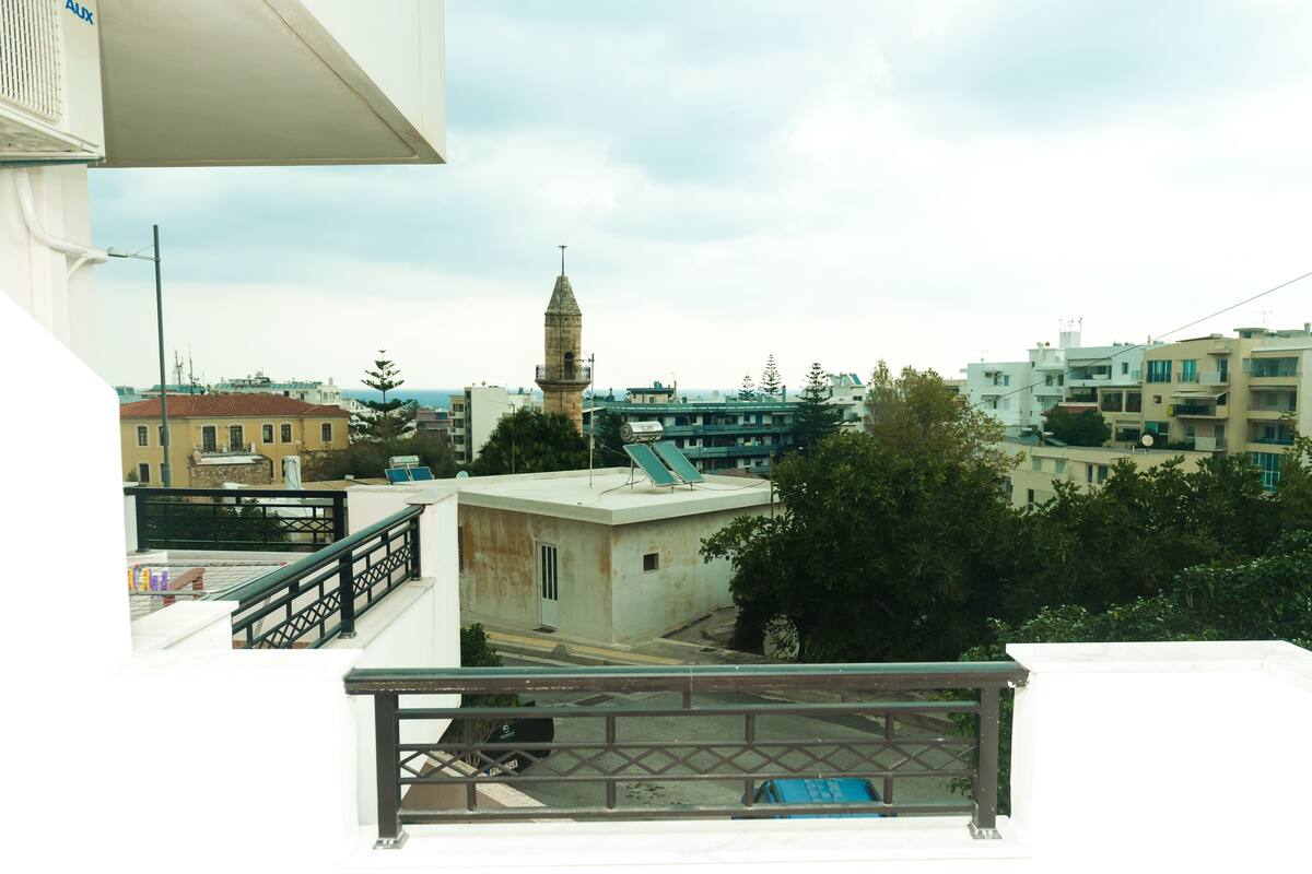 Un balcón con vistas a un paisaje urbano, que incluye una torre y edificios residenciales.