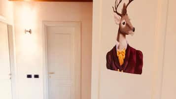 Un pasillo con una puerta blanca, techo de madera y un muro decorado con un ciervo.