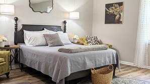 Une chambre à coucher bien aménagée, avec un grand lit, une table de chevet, un miroir et une œuvre d’art accrochée au mur.