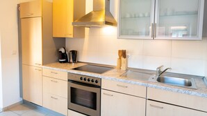 Een moderne keuken met roestvrijstalen apparatuur, een granieten aanrechtblad en houten keukenkastjes.