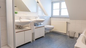 Een moderne badkamer met twee wastafels, een toilet en een raam.