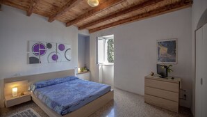 Una camera da letto con un letto, una cassettiera, una televisione e opere d'arte alle pareti.