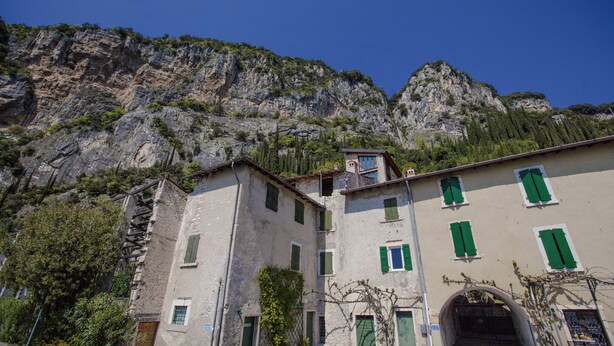 Un edificio con diverse finestre e facciata in pietra, sullo sfondo di montagne.