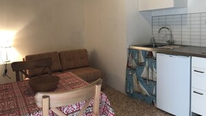 Una cucina compatta con lavandino, un piccolo armadietto e un angolo ristoro con una sedia e un tavolo.