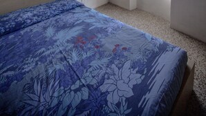 Una camera da letto con soffitto in legno, un letto con copripiumino floreale, una finestra vista e un muro con arte astratta.