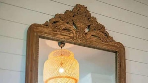 Une chambre avec un grand miroir, un lit avec une literie blanche et un luminaire suspendu.