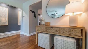 Un intérieur moderne avec une console en bois, un miroir rond et un lampadaire.
