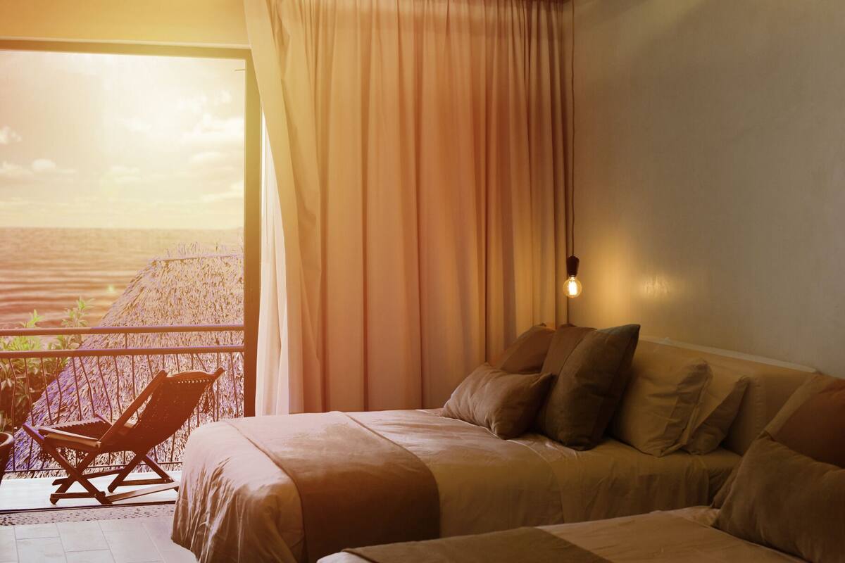 A bedroom with a bed, pillows, a nightstand, and a window with curtains.
