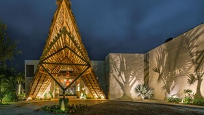 A modern building with a unique triangular roof structure, surrounded by a landscaped garden and a paved courtyard.