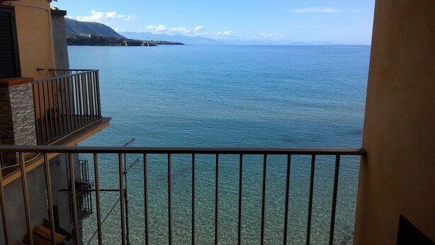 Un balcon offrant une vue dégagée sur une mer calme et des montagnes lointaines.
