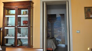 Un salon avec un meuble en bois, un lustre et une porte donnant sur une autre pièce.