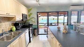A kitchen with a view to a balcony, a sink, a stove, and a countertop with a jar of stones.