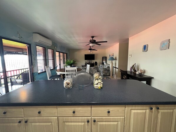 A kitchen with a large island, wooden cabinets, and a dining area with a table and chairs. - This Gorgeous Oceanview Condo is the Perfect Caribbean Retreat! (Christiansted)