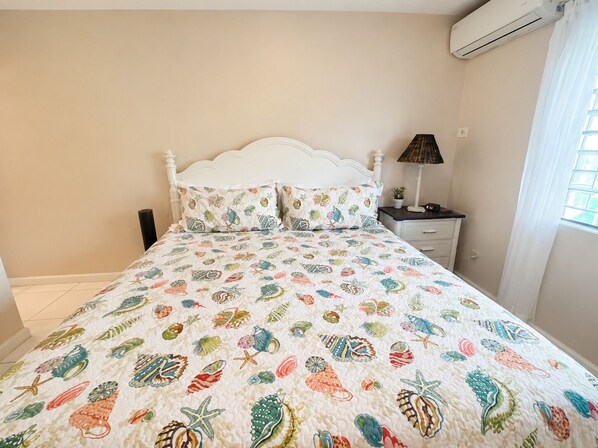 Un lit avec une tête de lit blanche et une couvre-lit colorée ornée de motifs représentant des créatures marines.