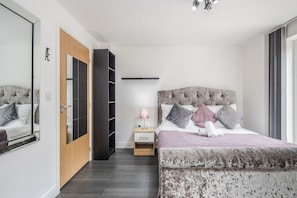 Une chambre à coucher avec un grand lit, une table de chevet, un miroir, une armoire et une étagère.