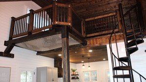 A spacious kitchen with wooden beams, a central island, and a staircase leading to an upper level.