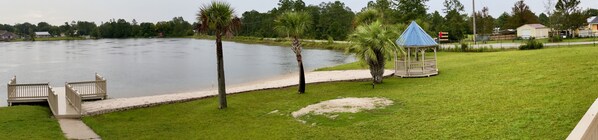 Vista de un lago con un pabellón, un muelle de madera y una zona verde.