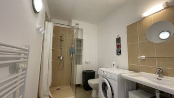 Ein modernes Badezimmer mit Dusche, Toilette und Waschmaschine.