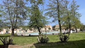 A pool surrounded by trees and a building with multiple balconies. - App. One-bedroom apartment with all the amenities, pool, patio, Wi-Fi, 500 m from the beach, parking, air conditioning. (Santa-Maria-Poggio)