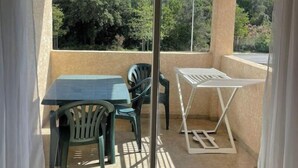 A balcony with a table and chairs, a view of trees, and a clear sky. - App. One-bedroom apartment with all the amenities, pool, patio, Wi-Fi, 500 m from the beach, parking, air conditioning. (Santa-Maria-Poggio)