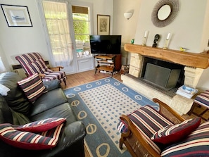 A living room with a sofa set, a television, a fireplace, and a patterned rug. - Central Cap Ferret location, all on foot A0342 (Cap Ferret)