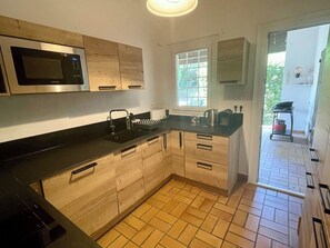 A modern kitchen with a microwave, sink, and wooden cabinets. - Central Cap Ferret location, all on foot A0342 (Cap Ferret)