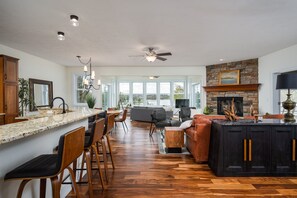 A spacious kitchen with a large island, wooden flooring, and a stone fireplace. - 5BR Saugatuck-Area Home with Incredible Views (Douglas)