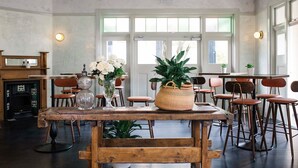 A dining area with a rustic wooden table, chairs, and potted plants. - Terminus Pyrmont (Pyrmont)