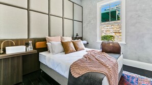 A bedroom with a bed, bedside table, and a window with a view of buildings. - Terminus Pyrmont (Pyrmont)