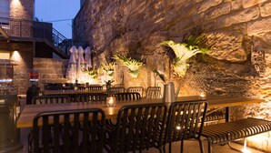 An outdoor restaurant with stone walls, wooden tables, and black metal chairs. - Terminus Pyrmont (Pyrmont)