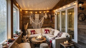A cozy cabin interior with a sofa, a round coffee table, and a fireplace.