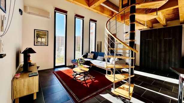 Una sala de estar moderna con una escalera espiral, ventanas amplias y una zona de estar acogedora.