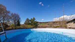 A swimming pool with clear blue water, surrounded by trees and a stone building. - A resort for groups surrounded by nature (Lavoine)