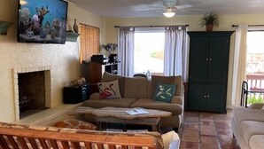 A living room with a fireplace, a ceiling fan, a television, and a green cabinet. - North Padre Island waterfront canal home w/private pool and dock (Corpus Christi)