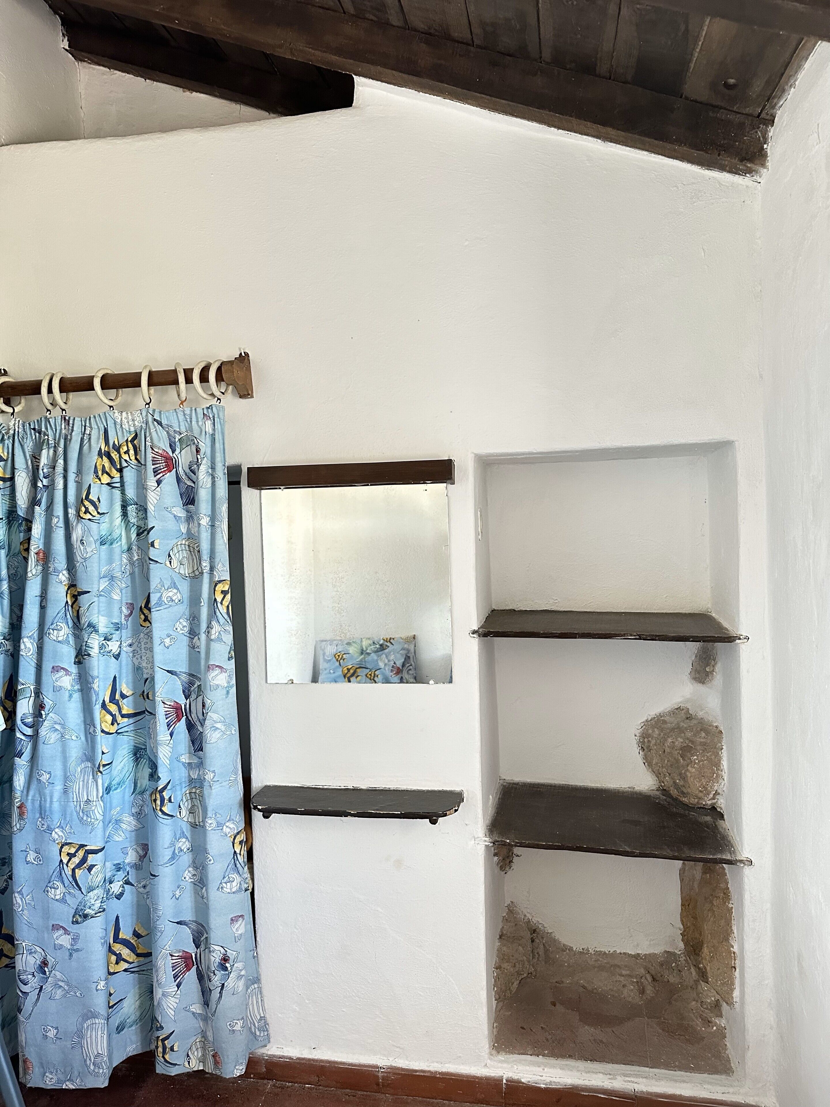 A bathroom with a shower curtain, a mirror, and three shelves.