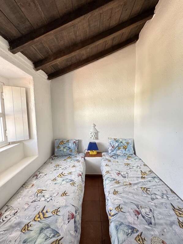 A small room with two single beds, a nightstand, a lamp, and a window with white shutters. - Serra da Arrábida fantastic view (Setúbal)