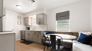A modern kitchen with grey cabinets, a dining table, and a seating area with a sofa and chairs.
