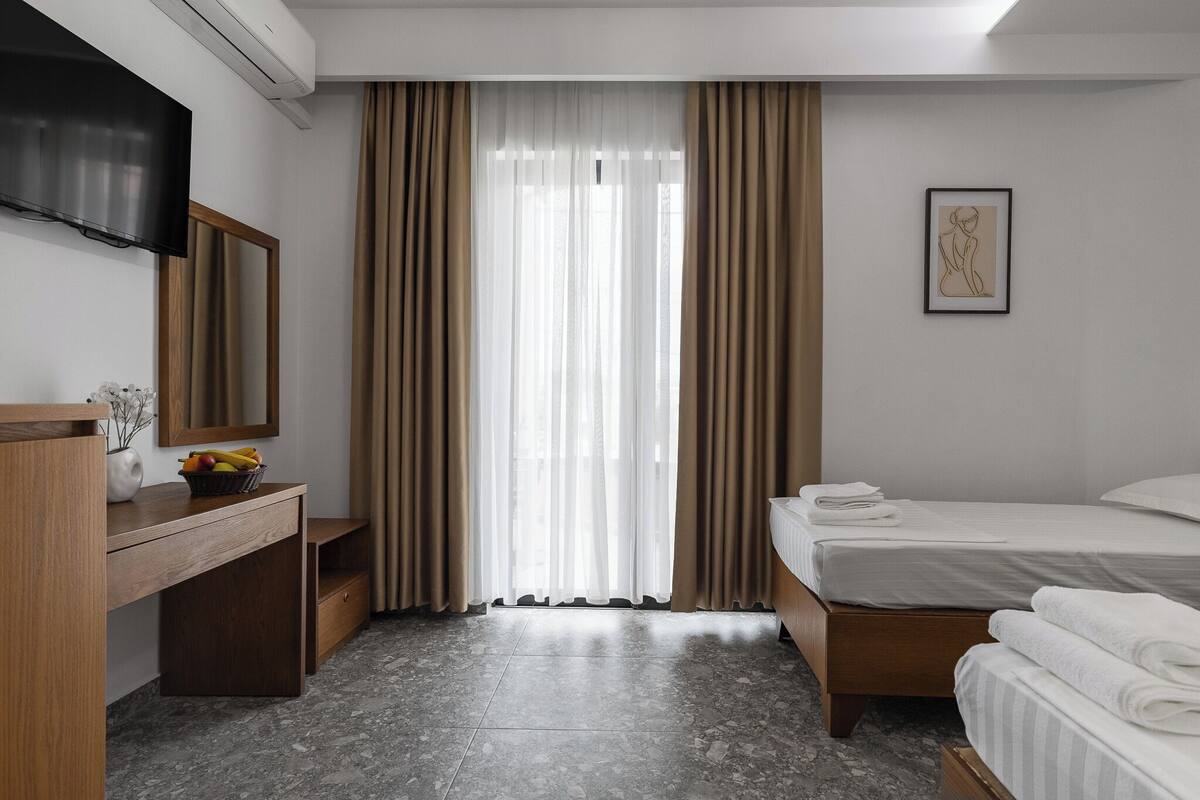 Une chambre d’hôtel avec un lit, un bureau doté d’un miroir, une télévision et une œuvre d’art encadrée accrochée au mur.