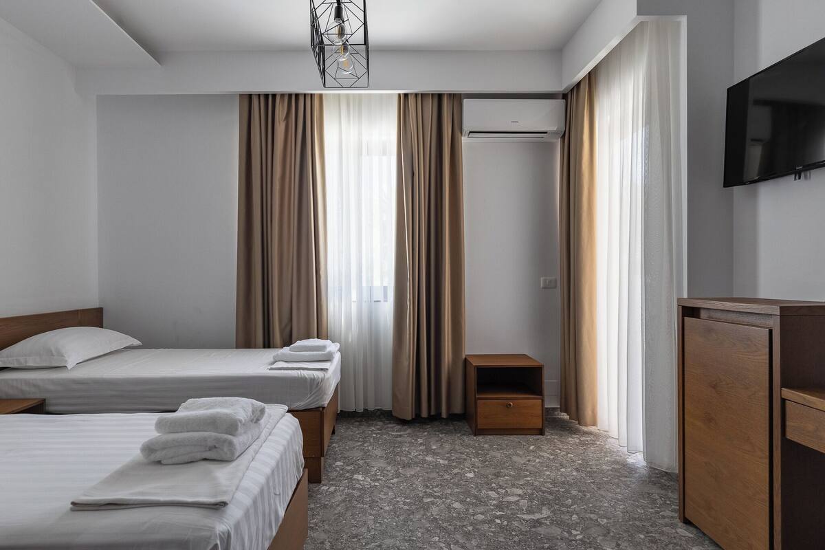 Une chambre d’hôtel avec deux lits, une armoire, un téléviseur et un appareil de climatisation.