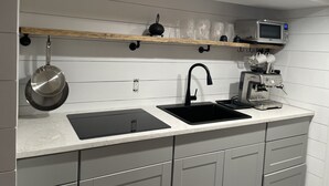 A modern kitchen with a built-in stove, a sink, and a microwave. - Hamptons Apartment in Lower Part of a House (Hampton Bays)