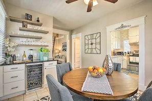 A modern kitchen with white cabinets, a built-in oven, and a dining area with a round table and chairs.