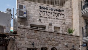 A multi-story building with balconies and air conditioning units. The facade has Hebrew text indicating it is a hotel. - Superb 1Bdr w balcony (Jerusalem)