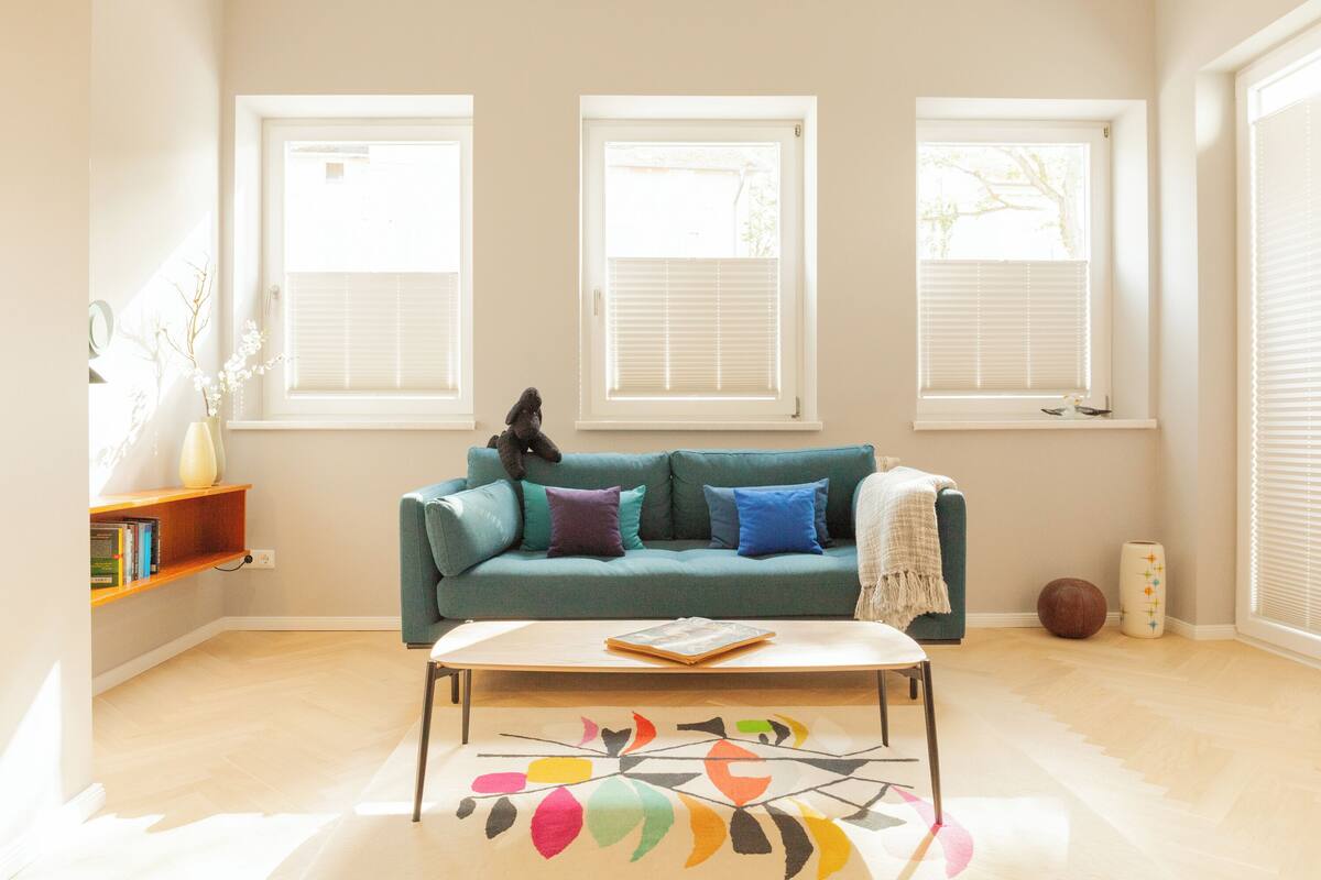Una sala de estar con un sofá color turquesa, una mesa de centro y una estantería.