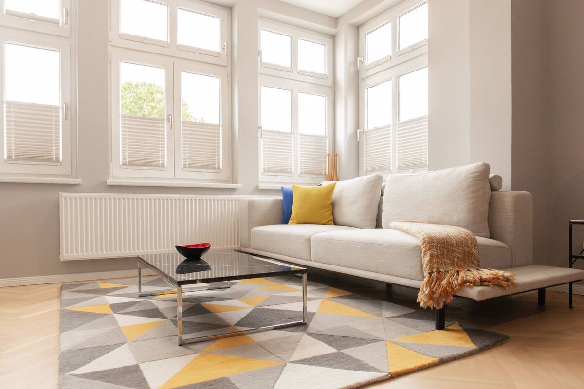 Una sala de estar moderna con sofá, mesa de centro y alfombra estampada.