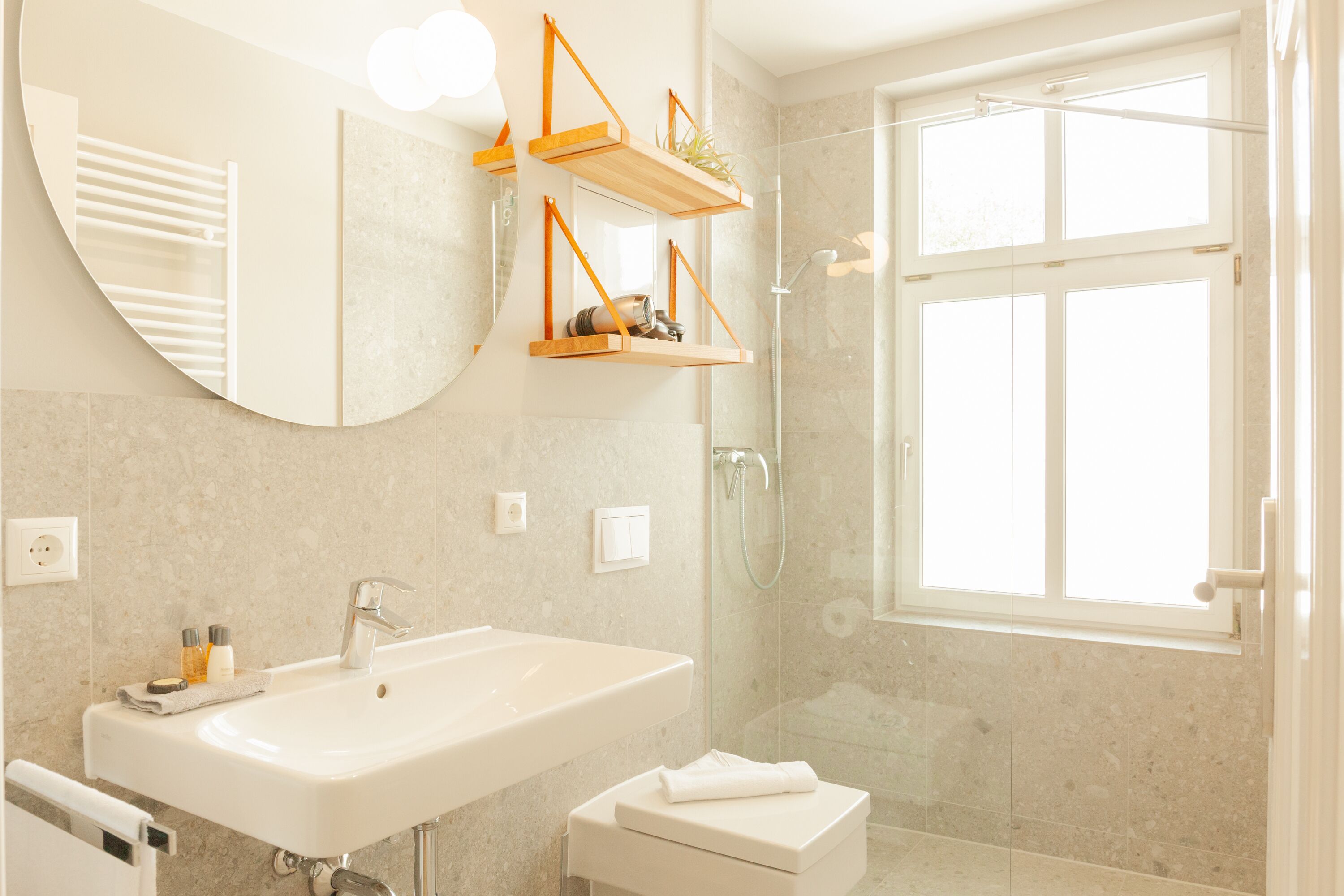 A modern bathroom with a large sink, a mirror, and a shower area.