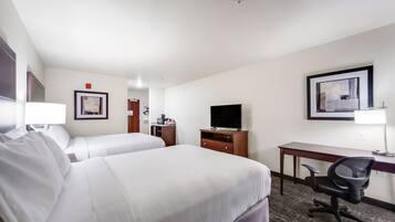Een hotelkamer met twee bedden, een bureau, een stoel, een televisie en een lijst met foto op de muur.