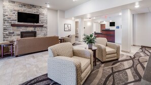 A lobby with a stone fireplace, a flat-screen TV, a reception desk, and comfortable seating. - Cobblestone Inn & Suites-Fremont (Fremont)