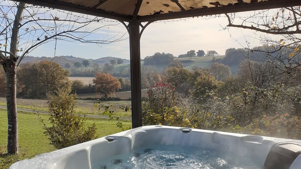 Un jacuzzi bajo una pérgola con vistas panorámicas del campo.